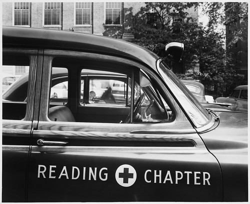 Symbols – Daytime, Red Cross – Ambulance, Close-up through Open Front Passenger Side Window Frame (Wood Trim), Windshield Lamp, Parked Cars, Brick Buildings Trees, 3:45 P.M.