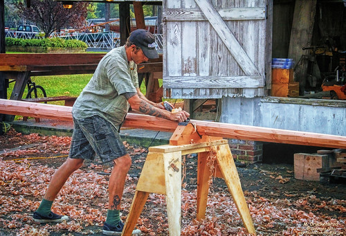 Woodworker Planing a replacement Ship Mast outside the Corn Crib