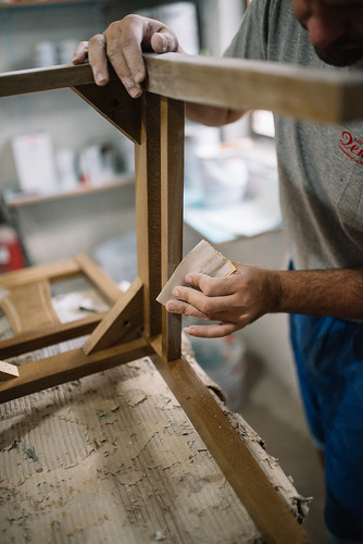 A workshop worker sanding a chair with sandpaper