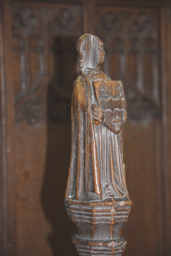 stall finial: celebrant holding a shield