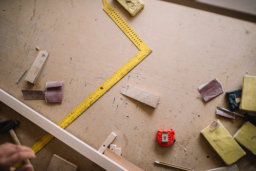 A ruler, a meter, sandpaper and a pen on a table in a furniture workshop