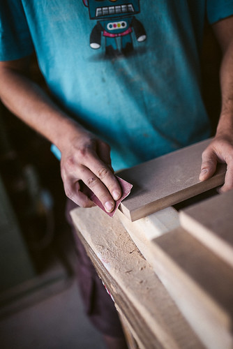 Young worker sanding a piece of wood