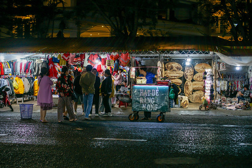 Man selling roasted Chestnuts in front of a Clothing Store at the Night Market in Dalat, Vietnam