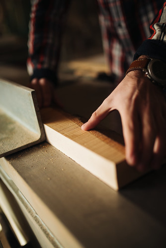 Carpenter measuring a piece of wood in his workshop.