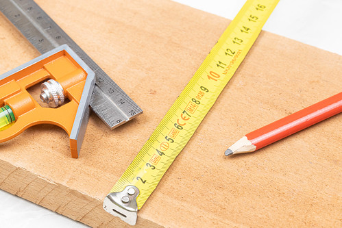 Combination square with wooden pencil and measuring tape on the wooden board