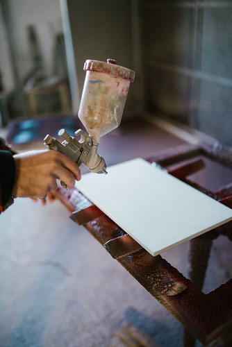 Close-up of carpenter painting a wood board in his workshop using a spray gun