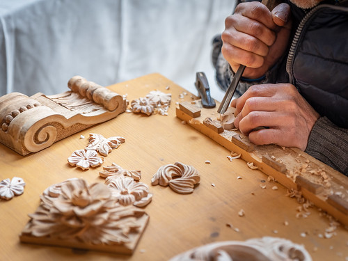 The hands of a craftsman carve wooden decorations