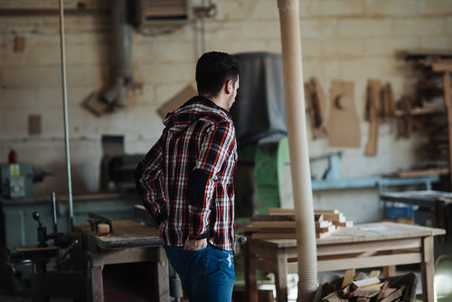 Carpenter wearing a plaid shirt standing in his workshop.